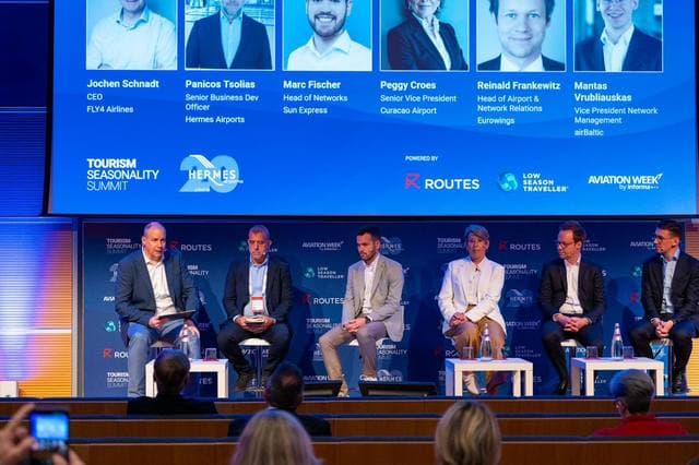 The value chain panel on stage, with the speaker line-up displayed behind