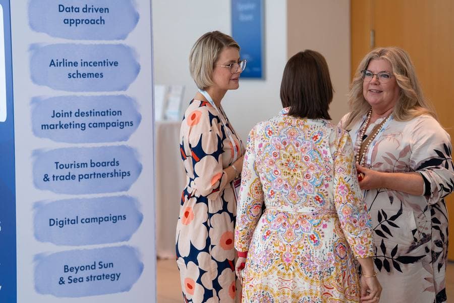 Delegates in conversation beside a Summit banner listing airline incentive schemes and joint destination marketing campaigns